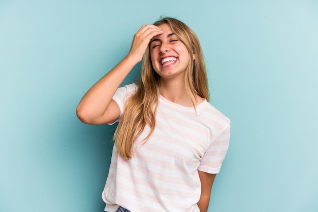 Joven mujer rubia caucásica aislada sobre fondo azul riendo feliz, despreocupada, emoción natural.