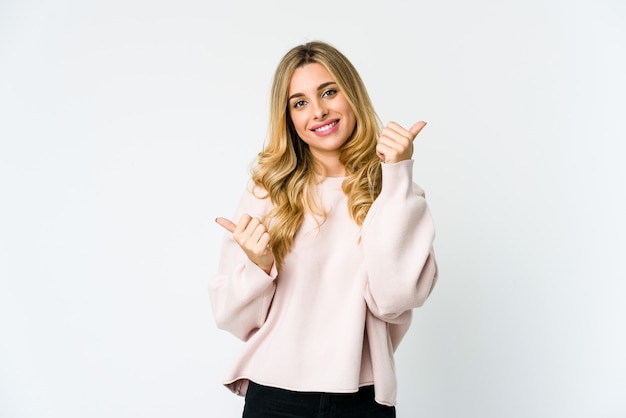 Joven mujer rubia caucásica levantando ambos pulgares, sonriente y confiada.