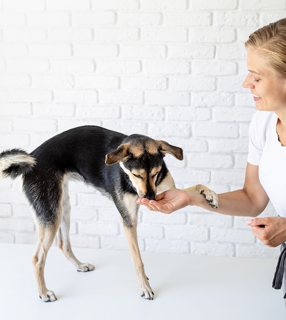 Foto joven mujer rubia dando un bocadillo a su perro