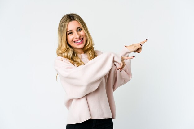 Joven mujer rubia emocionada apuntando con los dedos índices lejos