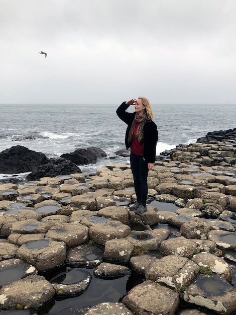 Joven mujer rubia se encuentra en la Calzada del Gigante en Irlanda del Norte Turista británico Gran Bretaña