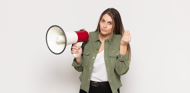 Foto joven mujer rubia haciendo gesto de capice o dinero, ¡diciéndole que pague sus deudas!