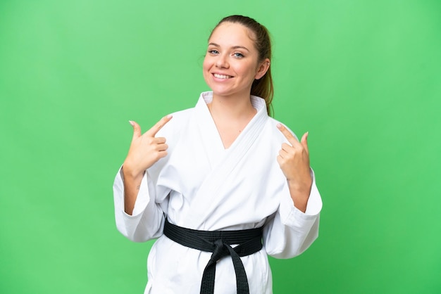 Joven mujer rubia haciendo karate sobre un fondo aislado de clave de croma dando un gesto de pulgar hacia arriba