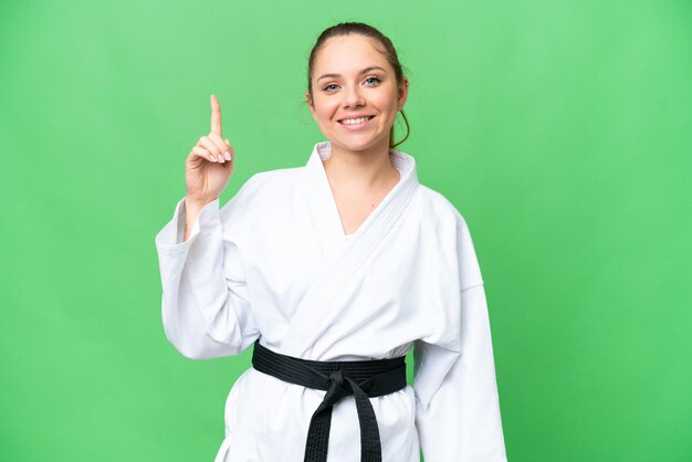 Joven mujer rubia haciendo karate sobre un fondo aislado de clave de croma que señala una gran idea