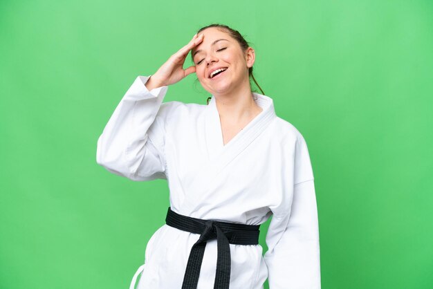 Joven mujer rubia haciendo karate sobre un fondo aislado de clave de croma sonriendo mucho