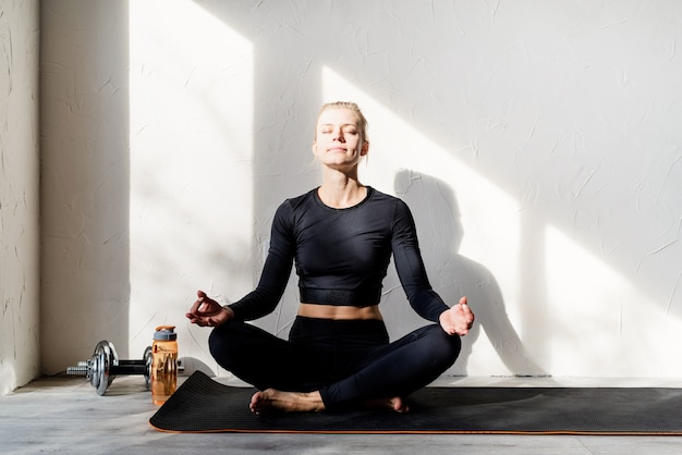 Joven mujer rubia haciendo yoga o meditando en casa