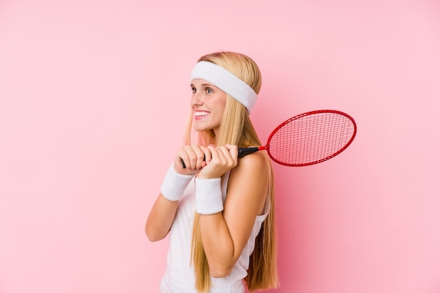 Joven mujer rubia jugando bádminton aislado