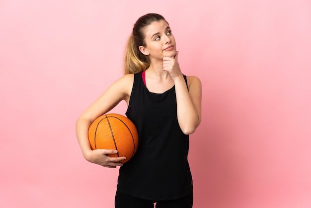 Joven mujer rubia jugando baloncesto aislado teniendo dudas