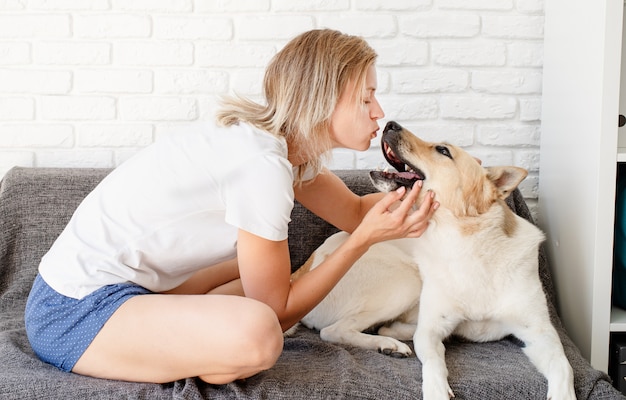 Joven mujer rubia jugando con su perro