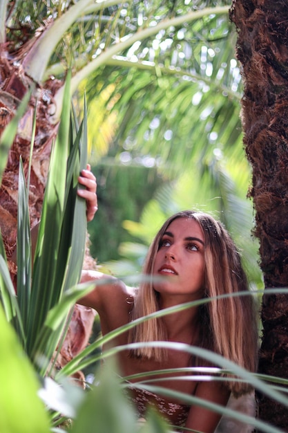 Foto joven mujer rubia mirando hacia arriba con ojos de color miel en el paraíso tropical