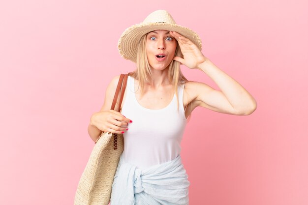 Joven mujer rubia mirando feliz, asombrado y sorprendido