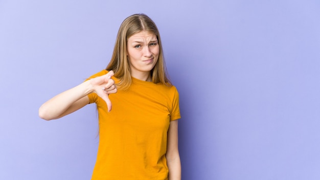 Joven mujer rubia mostrando el pulgar hacia abajo