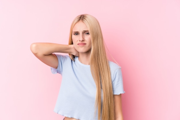 Joven mujer rubia en la pared de color rosa que sufren dolor de cuello debido al estilo de vida sedentario.