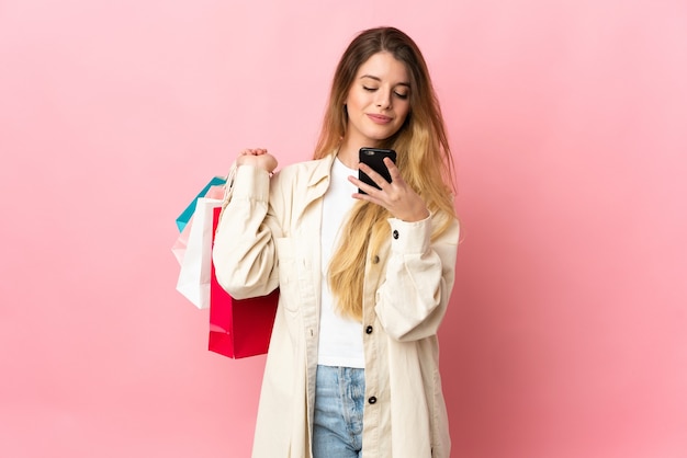 Joven mujer rubia posando aislada contra la pared en blanco