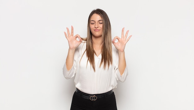 Foto joven mujer rubia que parece concentrada y meditando, sintiéndose satisfecha y relajada, pensando o tomando una decisión