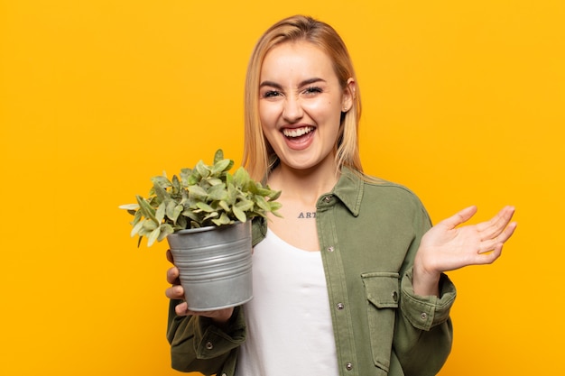 Joven mujer rubia que parece extremadamente feliz y sorprendida, celebrando el éxito, gritando y saltando