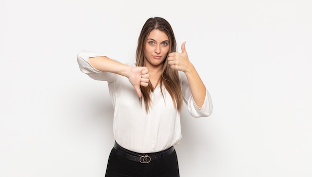 Foto joven mujer rubia que se siente confundida, desorientada e insegura, sopesando lo bueno y lo malo en diferentes opciones o elecciones