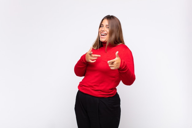 Joven mujer rubia que se siente feliz, fresca, satisfecha, relajada y exitosa, apuntando a la cámara, eligiéndote