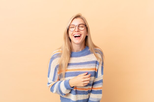 Joven mujer rubia riendo a carcajadas de una broma hilarante