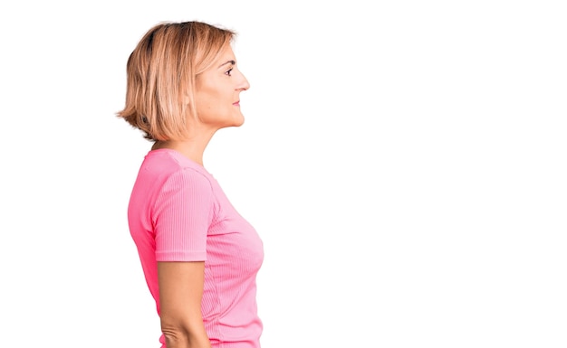 Joven mujer rubia con ropa deportiva mirando al lado relajarse pose de perfil con cara natural y sonrisa segura