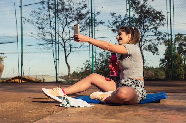 Joven mujer rubia sacando selfie mientras descansa después de un entrenamiento