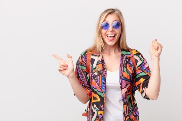 Joven mujer rubia sintiéndose conmocionada, riendo y celebrando el éxito