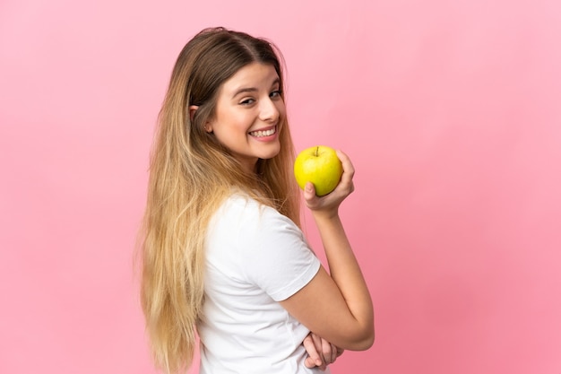 Joven mujer rubia sobre antecedentes aislados comiendo una manzana