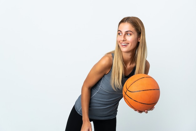 Joven mujer rubia sobre pared aislada jugando baloncesto