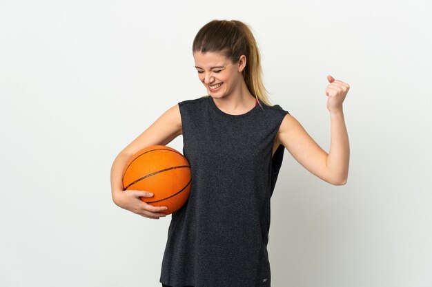 Joven mujer rubia sobre pared aislada jugando baloncesto