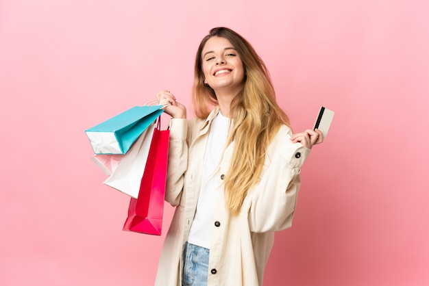 Joven mujer rubia sobre sosteniendo bolsas de compras aisladas y una tarjeta de crédito