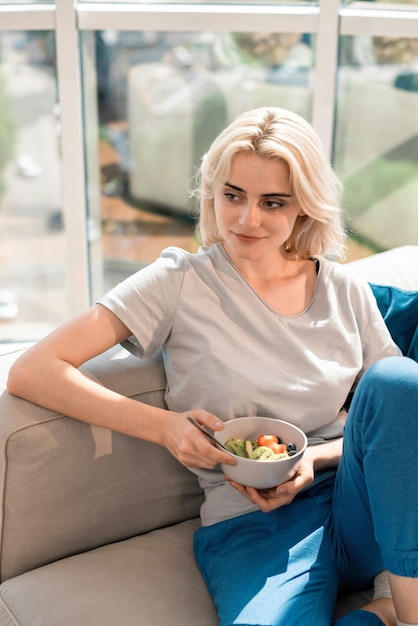 Joven mujer rubia en un sofá con gachas saludables