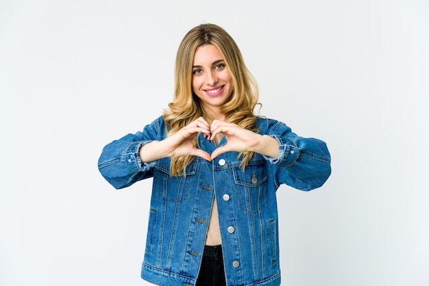 Joven mujer rubia sonriendo y mostrando una forma de corazón con las manos