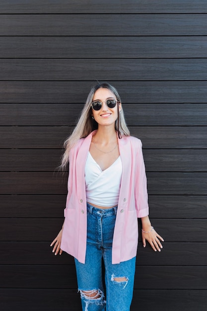 Joven mujer rubia sonriente contra una pared de madera apoyada con las manos. Empoderamiento femenino.