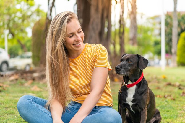 Joven mujer rubia con su adorable perro negro al aire libre