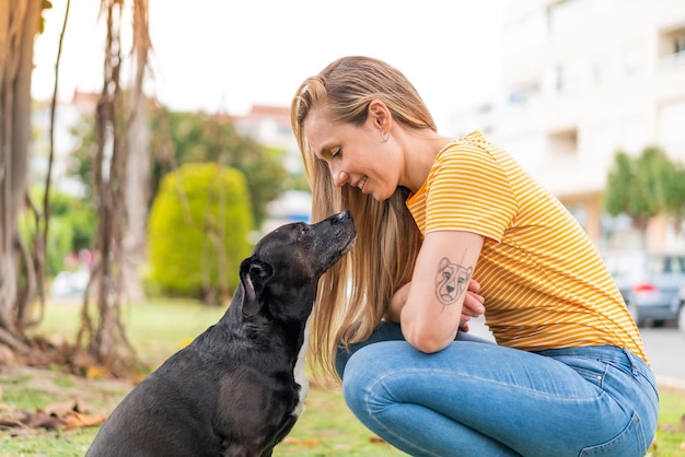Foto joven mujer rubia con su adorable perro negro al aire libre