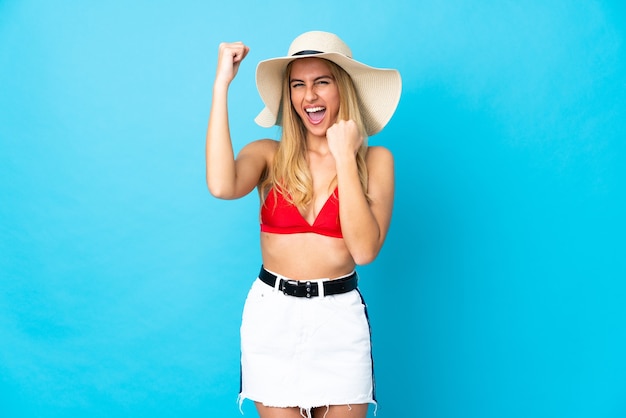 Foto joven mujer rubia uruguaya sobre fondo azul aislado en traje de baño en las vacaciones de verano