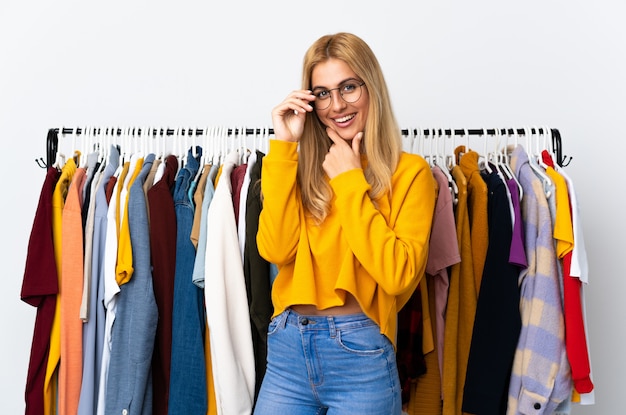 Joven mujer rubia uruguaya en una tienda de ropa con gafas y sonriente