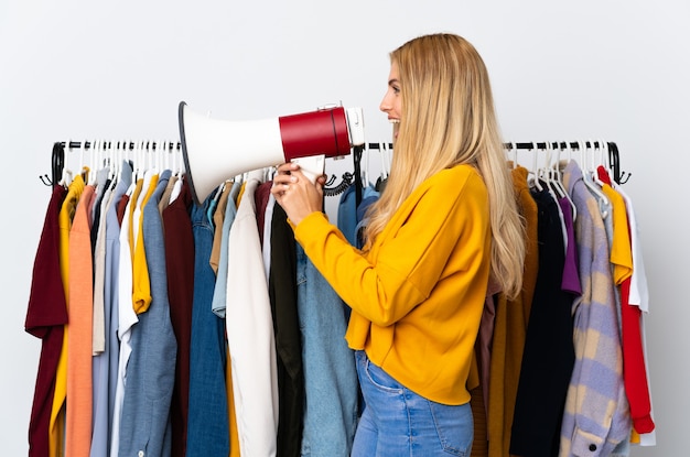 Joven mujer rubia uruguaya en una tienda de ropa gritando a través de un megáfono