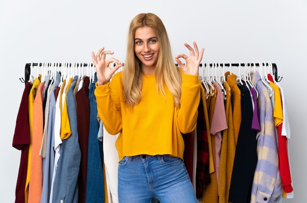 Joven mujer rubia uruguaya en una tienda de ropa mostrando un signo bien con los dedos
