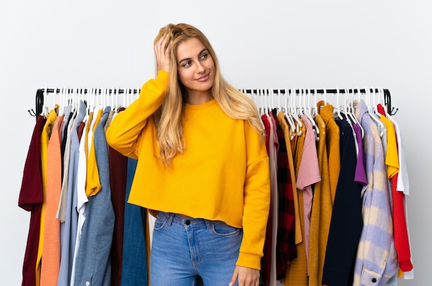 Joven mujer rubia uruguaya en una tienda de ropa pensando en una idea