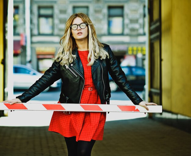 Joven mujer rubia con vestido rojo posando en la ciudad