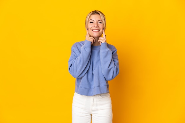 Joven mujer rusa aislada sobre fondo amarillo sonriendo con una expresión feliz y agradable