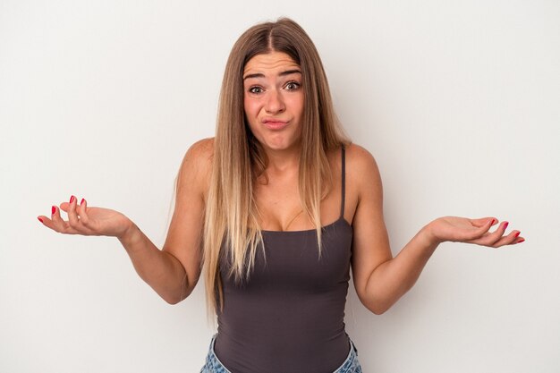 Foto joven mujer rusa aislada sobre fondo blanco dudando y encogiéndose de hombros en gesto de interrogación.