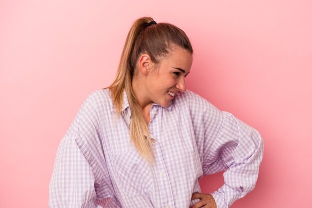 Joven mujer rusa aislada sobre fondo rosa sintiéndose enérgica y cómoda, frotándose las manos con confianza.