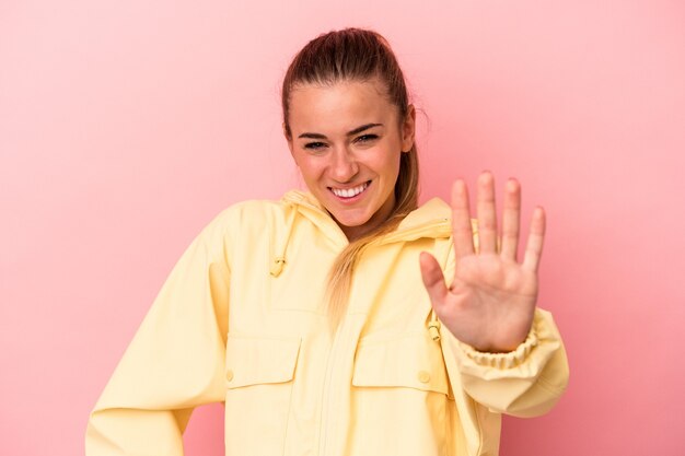 Joven mujer rusa aislada sobre fondo rosa sonriendo alegre mostrando el número cinco con los dedos.