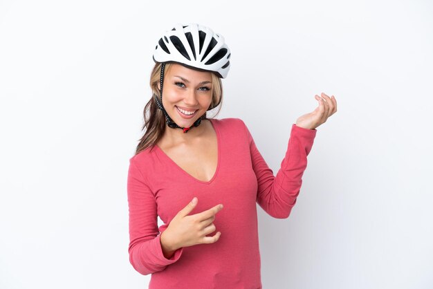 Joven mujer rusa con casco de bicicleta aislado de fondo blanco haciendo gestos de guitarra