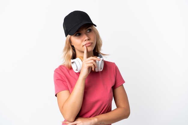 Joven mujer rusa escuchando música aislado sobre fondo blanco teniendo dudas mientras mira hacia arriba