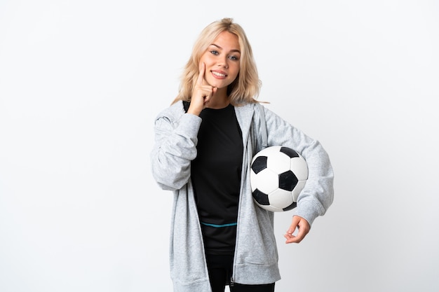 Joven mujer rusa jugando al fútbol aislado en la pared blanca sonriendo con una expresión feliz y agradable