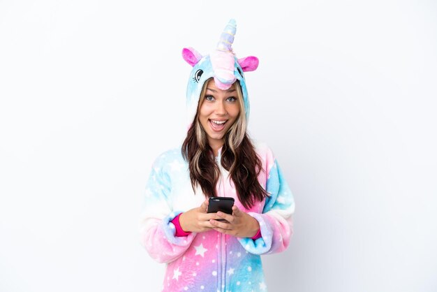 Joven mujer rusa con un pijama de unicornio aislada de fondo blanco sorprendida y enviando un mensaje