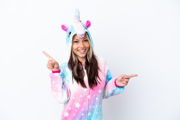 Joven mujer rusa con un pijama de unicornio aislado de fondo blanco señalando con el dedo a los laterales y feliz